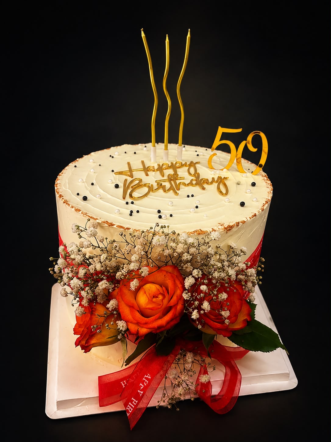 Geburtstagstorte mit roten Rosen, goldenem Happy-Birthday-Topper und funkelnden Kerzen